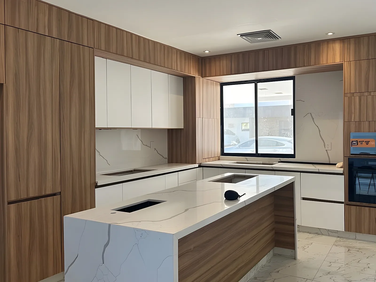 Cocina integral con muebles de madera, gabinetes blancos e isla con cubierta de cuarzo