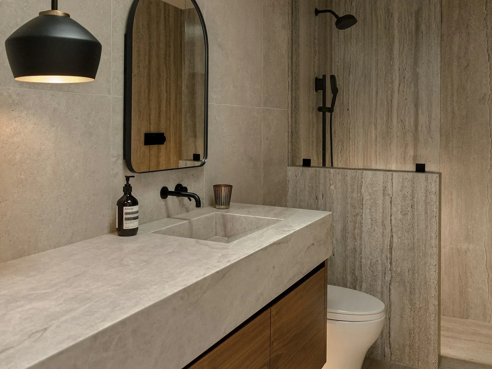 Baño con mueble flotante de madera y cubierta de piedra