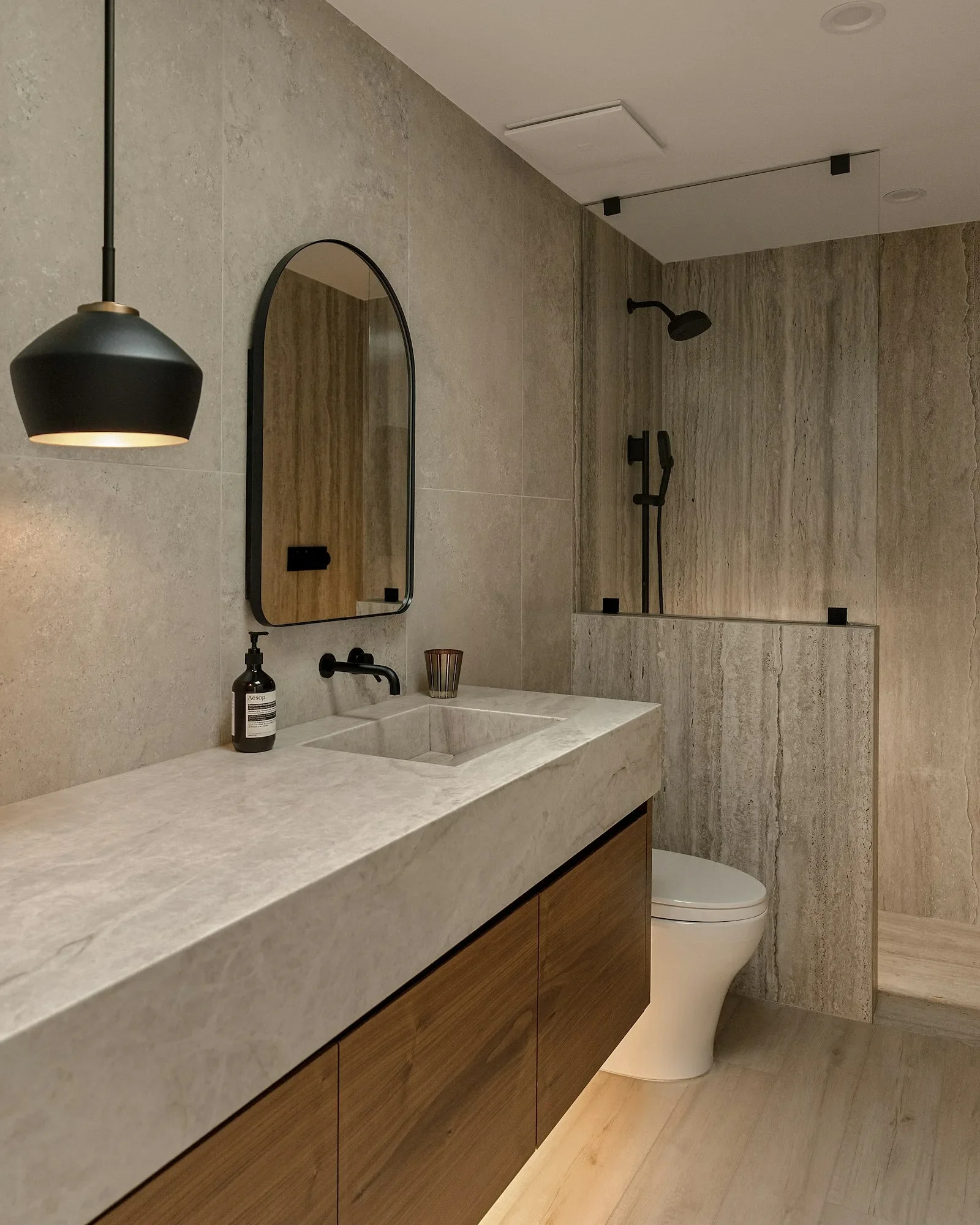Baño moderno con mueble flotante de madera y cubierta de piedra