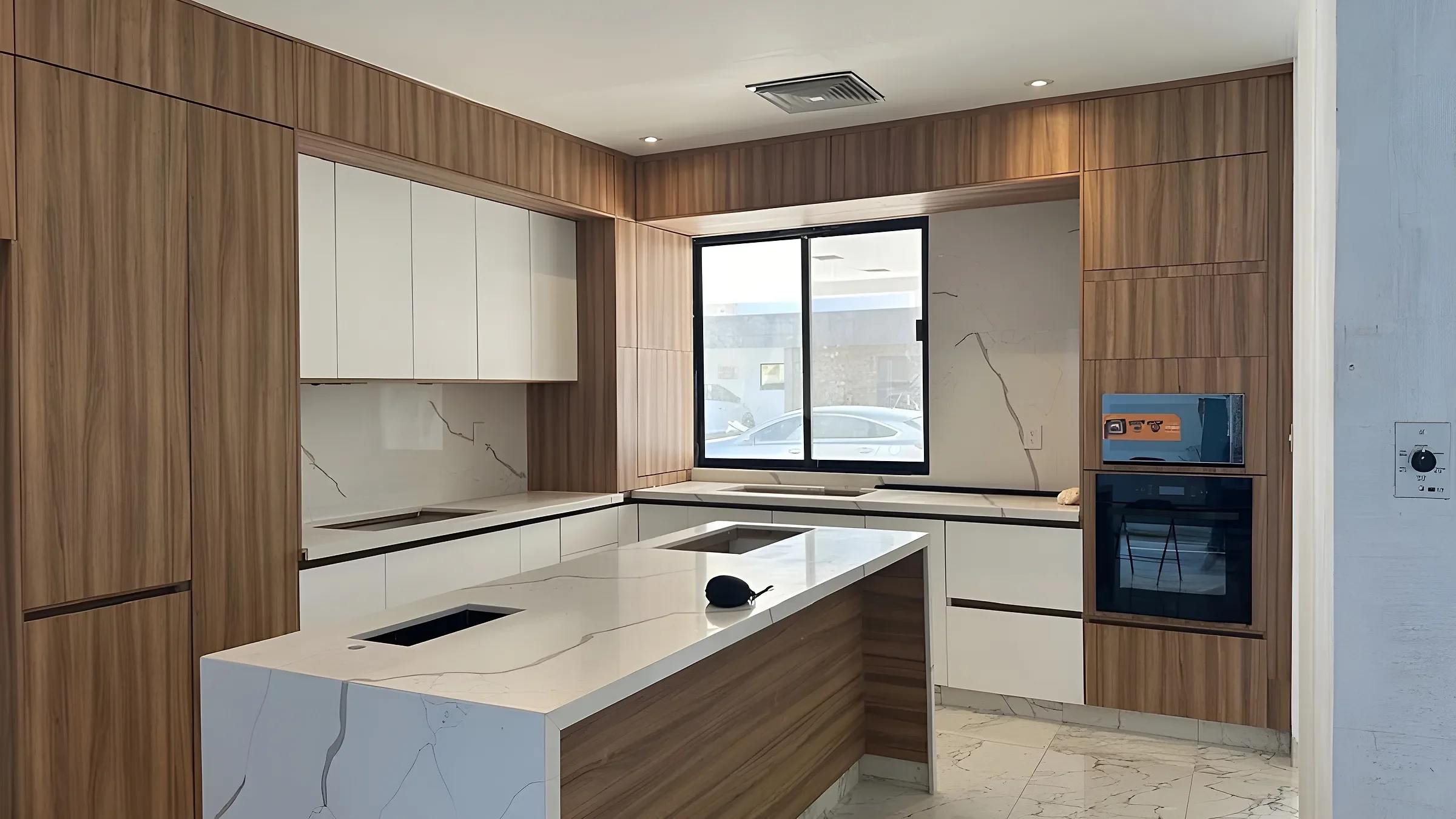 Cocina integral con muebles de madera, gabinetes blancos e isla con cubierta de cuarzo
